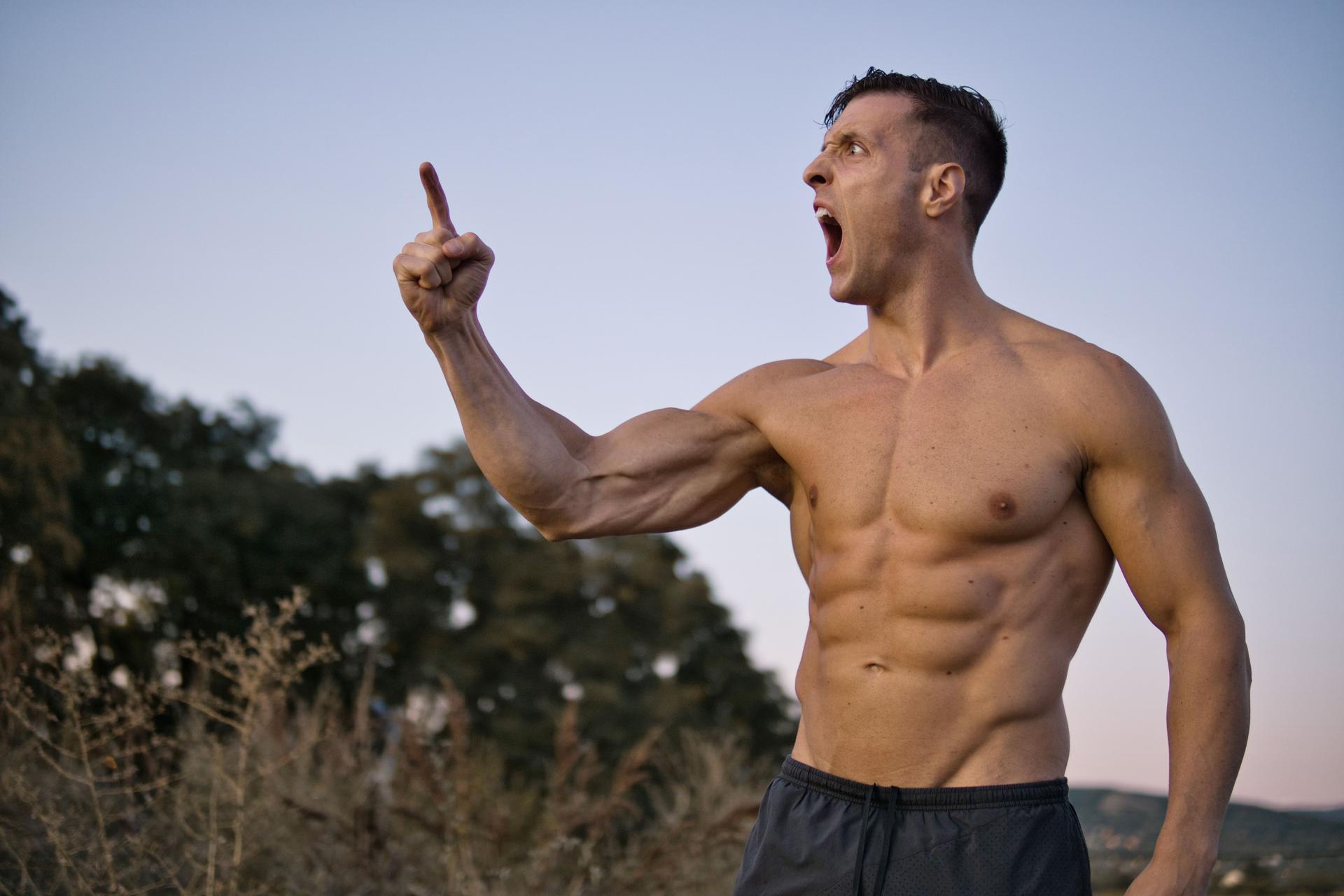 Portrait of muscular aggressive man showing muscle, isolated on a beautiful landscape.