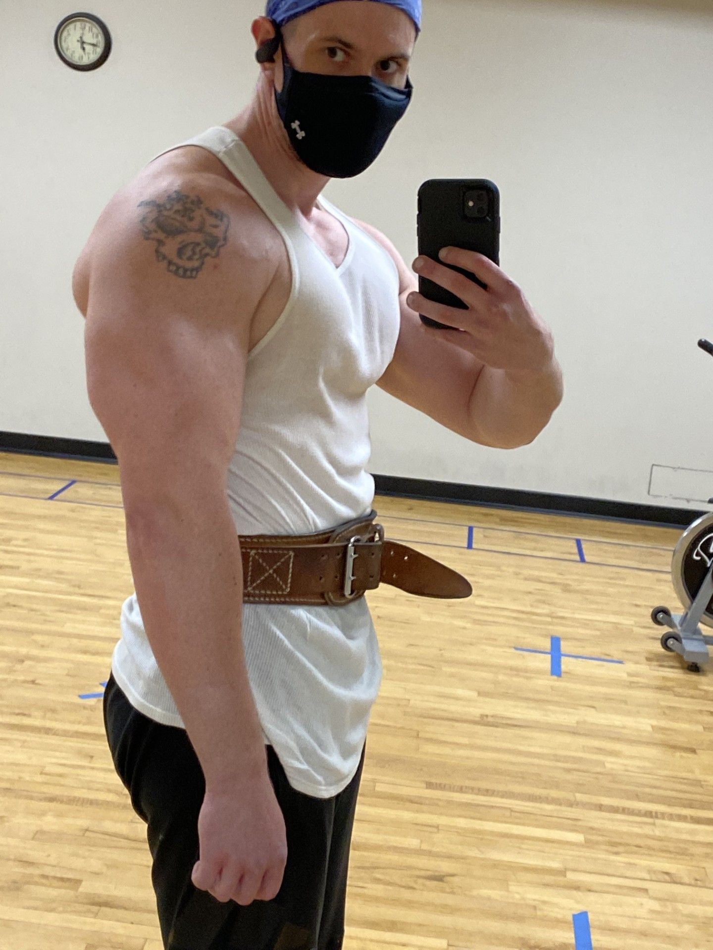 Person in gym attire taking a selfie while wearing a face mask and a weightlifting belt.